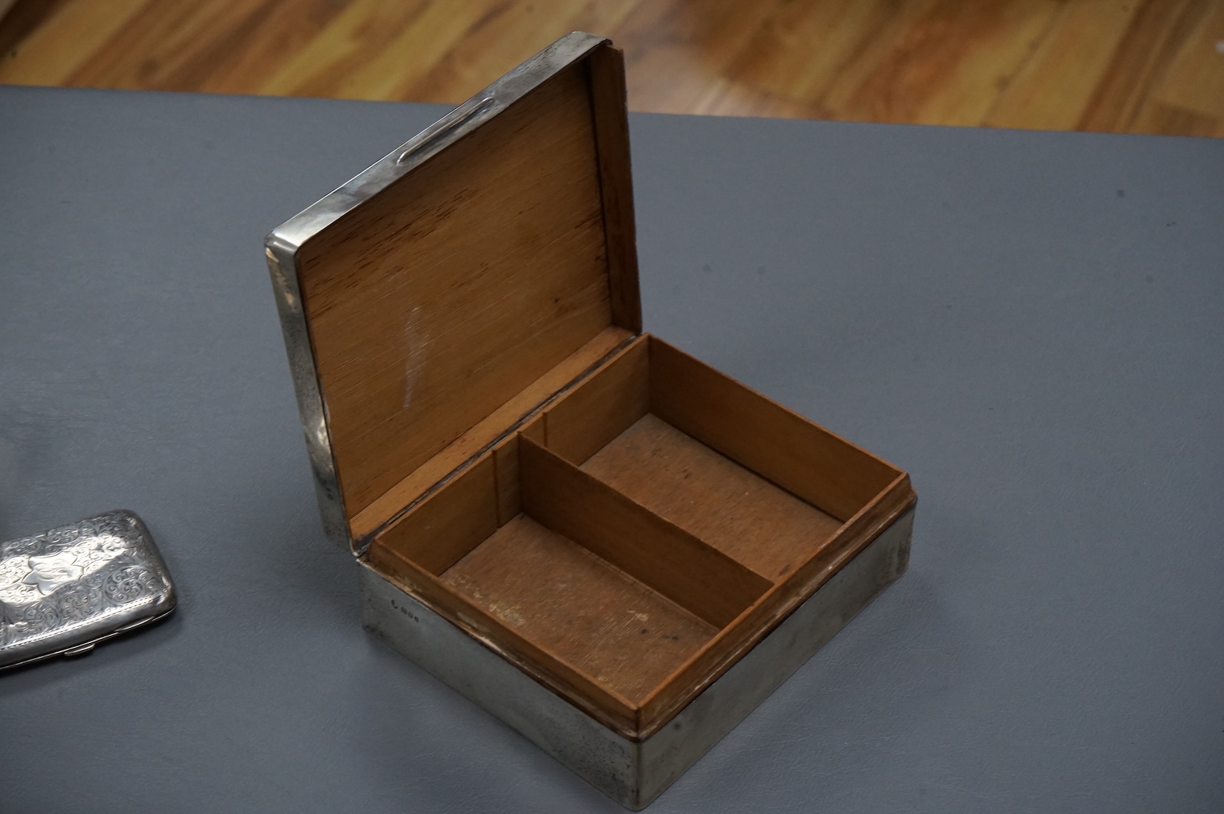 A George V silver mounted rectangular cigarette box, London, 1924, width 16cm, together with a smaller silver mounted cigarette box and a silver cigarette case.
